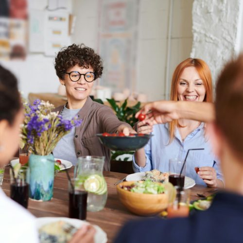 Eine Gruppe Menschen sitzt an einem Tisch und es wird eine Schüssel mit Essen in die Mitte gereicht